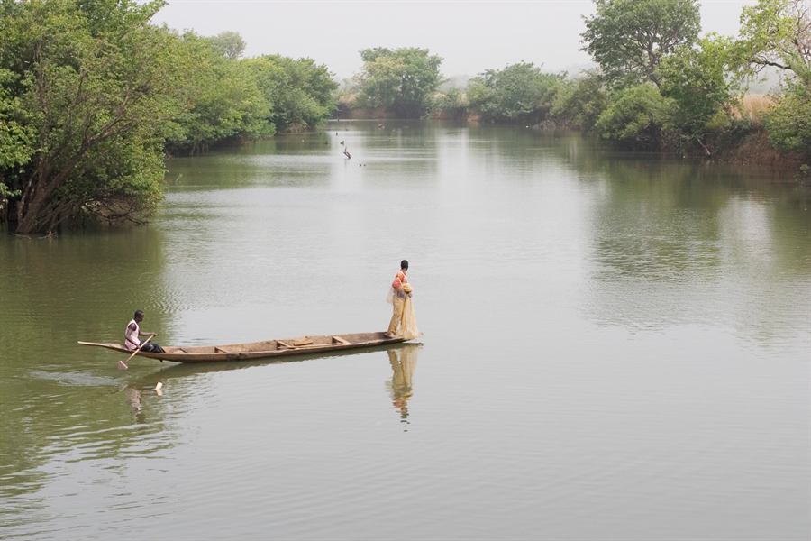 A fisherman casting a net from a pirogue on the Niger